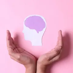 Dłonie otaczają profil głowy z mózgiem, symbolizując brak emocji po traumie i potrzebę wsparcia.