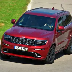 Czerwony Jeep Grand Cherokee z tablicami indywidualnymi małopolskimi na torze wyścigowym.