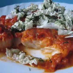 Pyszny dorsz z piekarnika w sosie pomidorowym, udekorowany świeżym koperkiem i chrupiącą kapustą.