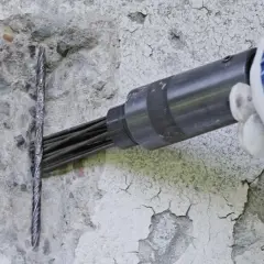 Narzędzie pneumatyczne przygotowuje beton do naprawy na zewnątrz.