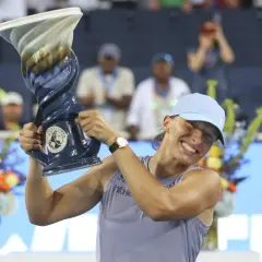 Iga Świątek triumfuje po wygranym finale, unosząc puchar.