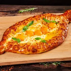Chaczapuri adżarskie z rozpływającym się serem i jajkami, idealne na ucztę w restauracji gruzińskiej w Katowicach.