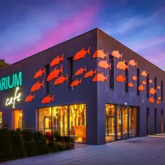 Oceanarium w Międzyzdrojach, z neonowym napisem i pomarańczowymi rybkami na fasadzie, to świetne miejsce na międzyzdrojskie atrakcje dla dzieci.