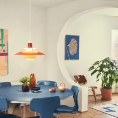 Ein Esszimmer im **mid century modern** Stil mit blauem Tisch, blauen Stühlen, einer bunten Wandkunst und einer markanten Hängeleuchte.