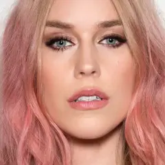 Kobieta z włosami w odcieniu strawberry blonde, z niebieskimi oczami i delikatnym makijażem.