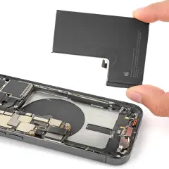 Wymiana baterii w iPhone 16. Dłoń trzyma nową baterię, gotową do montażu w otwartym telefonie.