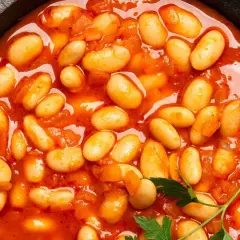 Pyszna fasolka po bretońsku przepis w garnku. Aromatyczne danie z białej fasoli w sosie pomidorowym, ozdobione natką pietruszki.