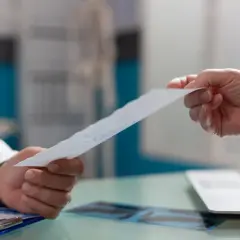 Lekarz przekazuje pacjentowi dokument, prawdopodobnie wniosek o świadczenie rehabilitacyjne.