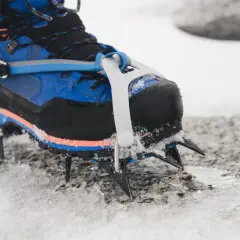 Niebieskie buty górskie z zamontowanymi rakami koszykowymi, gotowe na lodowe wyzwania.