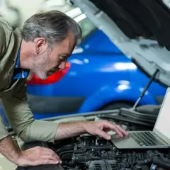 Mechanik z laptopem przy silniku samochodu.