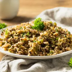 Plato de arroz integral con carne molida y verduras, decorado con perejil fresco.