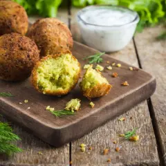 Chrupiące kulki falafel kebab na desce, obok sosu i świeżego koperku. Idealna przekąska.