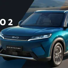 BYD ATTO 2 DM-i, un SUV blu metallizzato che sfreccia su una strada panoramica.