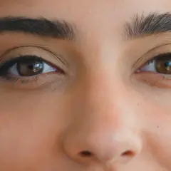 Brązowe oczy z subtelnym makijażem podkreślającym ich kształt, tworzącym efekt rzęsy foxy eyes.