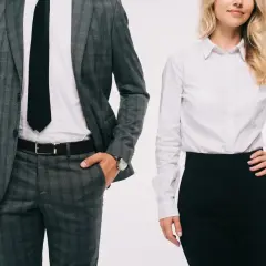 Elegancki mężczyzna w garniturze i kobieta w białej koszuli i czarnej spódnicy, prezentujący profesjonalny dress code.