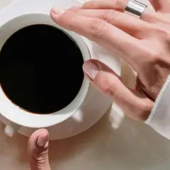 Händer som håller en kopp svart kaffe, en påminnelse om nackdelar med kaffe som sömnlöshet och oro.