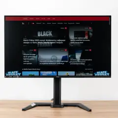 Monitor z widocznym na ekranie portalem Pcelite.pl, prezentującym artykuły o tematyce technologicznej, w tym promocje z okazji Black Friday. Test matrycy monitora jest kluczowy dla oceny jakości obrazu.