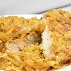 Schab w kapuście kiszonej, danie Ani, wygląda apetycznie. Mięso jest soczyste, a kapusta lekko zrumieniona.