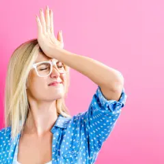Oups, j'ai oublié de signer la lettre de désolidarisation de bail ! Cette femme se frappe le front, l'air désemparé, sur fond rose.