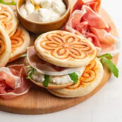Tavola con crescentine, affettati e formaggio cremoso, un assaggio dei piatti tipici bolognesi.