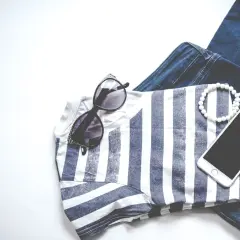 Stylizacja na Vinted: jeansy, bluzka w paski, okulary, bransoletki i telefon. Chcesz wiedzieć, jak obniżyć cenę na Vinted?