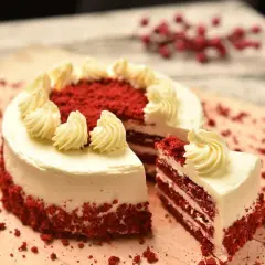 Pastel red velvet con glaseado blanco y decoraciones de crema. Una rebanada muestra las capas rojas y blancas. ¡Perfecto para tu próxima red velvet receta!