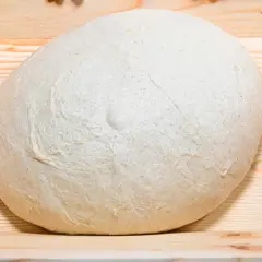 Impasto lievitato per pizza in casa, pronto per essere steso su un tagliere di legno.