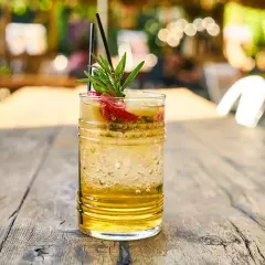 Orzeźwiający drink z marakują, lodem i gałązką rozmarynu na drewnianym stole.