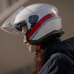 Donna con casco bianco e strisce rosse e blu, un esempio di diversi tipi di casco per la sicurezza in moto.