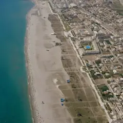Vista aérea de la playa Las Marinas Vera, con el mar turquesa, arena dorada y un complejo residencial con piscinas.