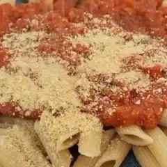Penne mit Tomatensauce und veganem Parmesan bestreut. Ein köstliches, pflanzliches Gericht.