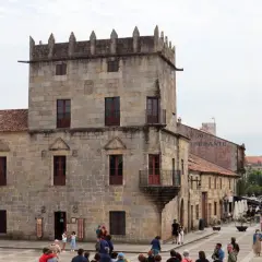 Plaza de Cambados que ver: torre medieval de piedra, casas históricas y gente paseando.