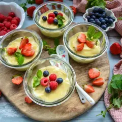 Vier Gläser mit selbstgemachtem Pudding, garniert mit frischen Beeren und Minze. Ein Genuss für Augen und Gaumen!