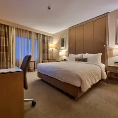 Komfortowy pokój hotelowy, idealny po długim locie tureckimi liniami lotniczymi. Duże łóżko, biurko i przytulne oświetlenie.