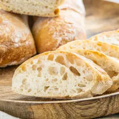 Frisch gebackene Ciabatta-Brote, aufgeschnitten auf einem Holzbrett. Dieses Ciabatta Rezept ergibt luftiges Brot mit knuspriger Kruste.