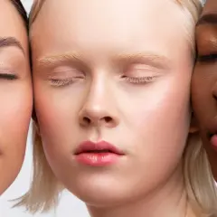Trois visages aux teints variés, aux yeux clos, sublimés par un maquillage discret et naturel.