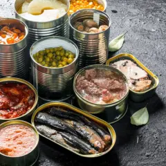 Variedad de latas abiertas con comida supervivencia: guisantes, champiñones, sardinas, carne y más.