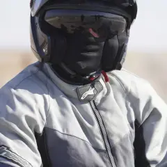 Motociclista con casco y pasamontañas, listo para viajar sin pasar frío en moto.