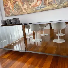 Specchio sopra madia riflette sedie bianche e un dipinto antico.