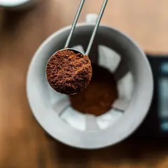 En skopa finmalet kaffe hälls ner i en filterhållare. Perfekt för att mäta rätt mängd gram kaffe per liter vatten för en balanserad bryggning.