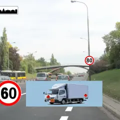 Na drodze widać znak w21 informujący o końcu obszaru zabudowanego. Obok znak ograniczenia prędkości do 60 km/h. W tle jadą samochody i autobusy.