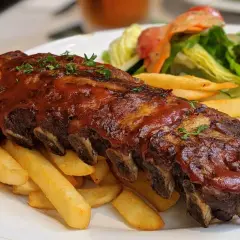 Soczyste żeberka w sosie BBQ, podane z chrupiącymi frytkami i świeżą sałatką. Prawdziwa uczta dla podniebienia!