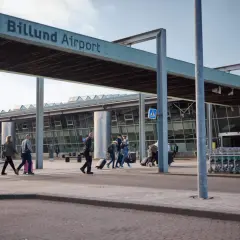 Människor med resväskor korsar vägen vid Billund Airport, redo att flyga till Legoland.