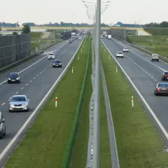 Ruch na drogach szybkiego ruchu w Polsce. Samochody poruszają się po wielopasmowej autostradzie, otoczonej zielenią i ekranami akustycznymi.