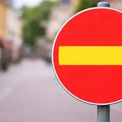 En röd cirkel med ett gult streck i mitten. En stoppskylt som signalerar stopp.