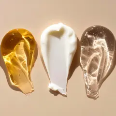 Tre olika krämsvansar: en gyllene olja, en vit kräm och en klar gel. Kanske en innehåller retinol, vitamin A för hudvård.