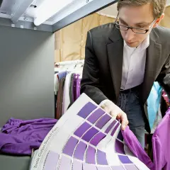 Un ingénieur textile examine des échantillons de couleurs violettes, comparant une chemise à un nuancier.