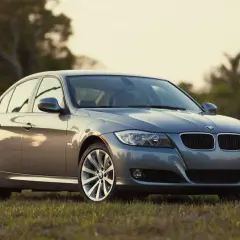 Szary sedan BMW na trawie. Klasyczne rodzaje karoserii, jak ten, są ponadczasowe.