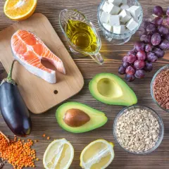 Assortiment d'aliments anti cholestérol : saumon, avocat, noix, lentilles, riz rouge, aubergine, agrumes, huile d'olive.
