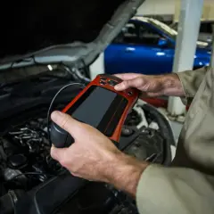 Mechanik z urządzeniem diagnostycznym przy silniku. Czy odłączenie akumulatora na chwilę pomoże zresetować komputer?